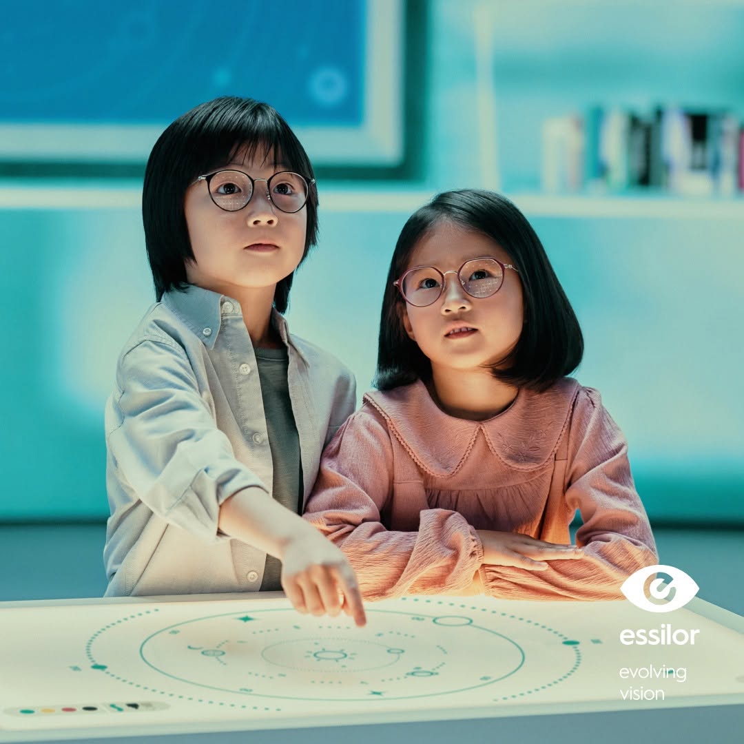 Hai trẻ em đeo kính Stellest học tập cùng logo Essilor